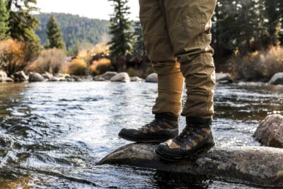 person in hiking boots standing in a river
