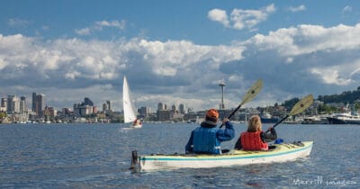 Two people kayaking on Lake Union with Seattle skyline behind them