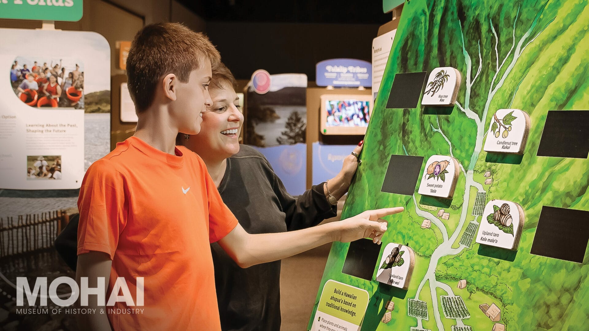 Photo of a young boy and adult interacting with a tribal heritage exhibit in a museum